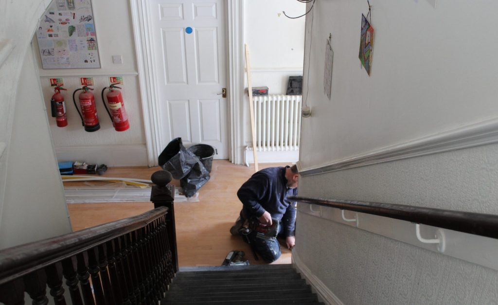 A maintenance worker carrying out repairs in a residential building hallway