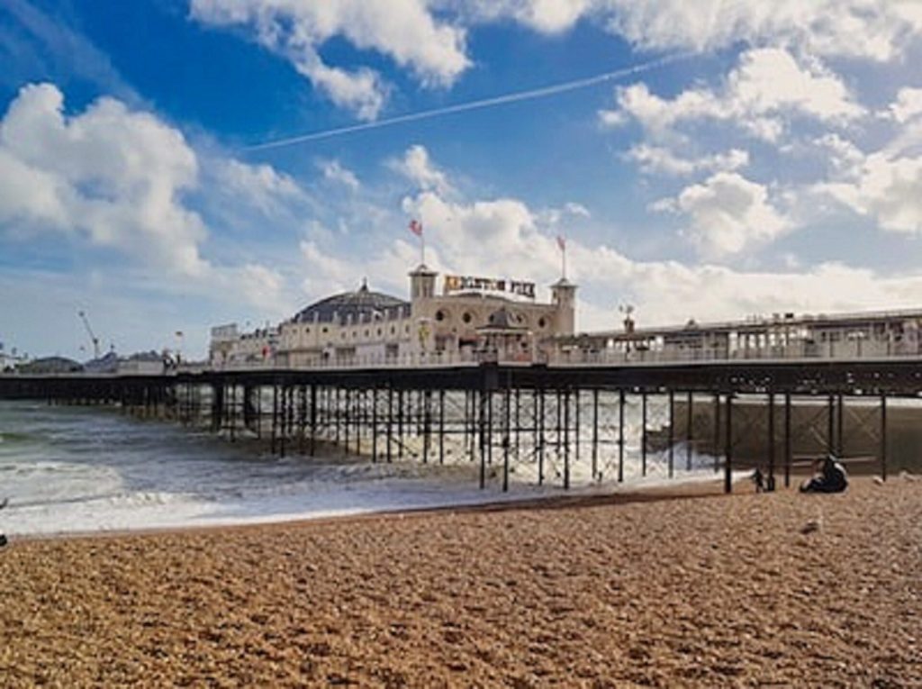 An image of Brighton Palace Pier with blue skies and big white clouds in the background