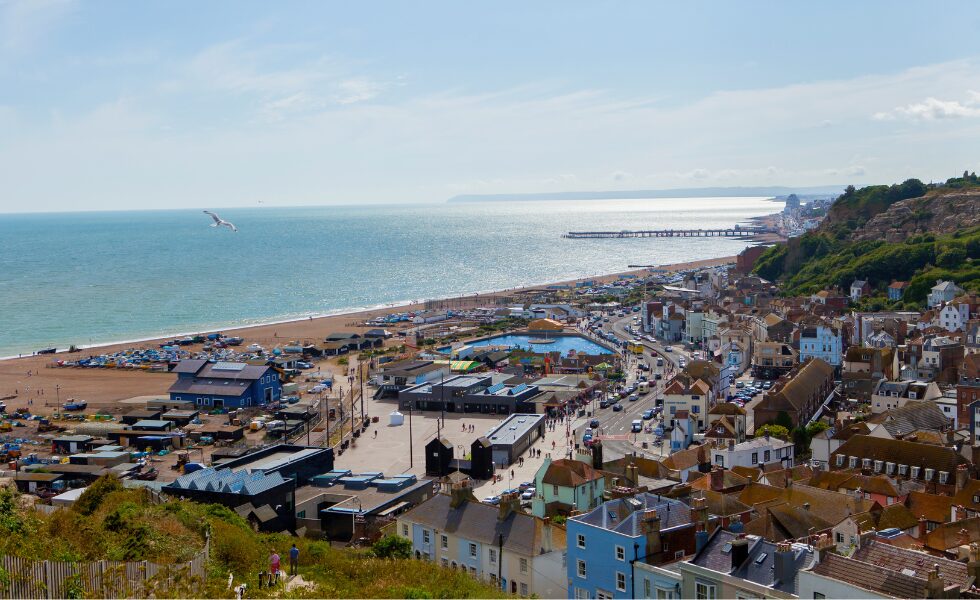 A landscape image of Hastings town and seafront. The sea is in the background.|Sussex communities