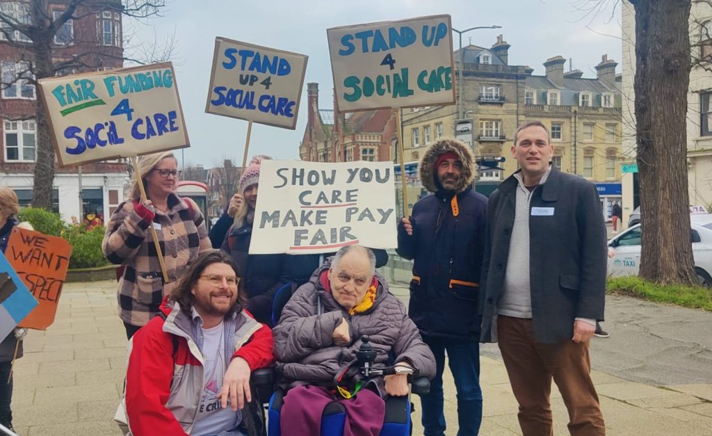 A group of Southdown employees accompanied by a client stand outside Hove town hall with placards asking for fair funding for social care from the local council.|||||||||A group of Southdown employees with a client stand outside Hove town hall with placards asking for fair funding for social care from the local council.